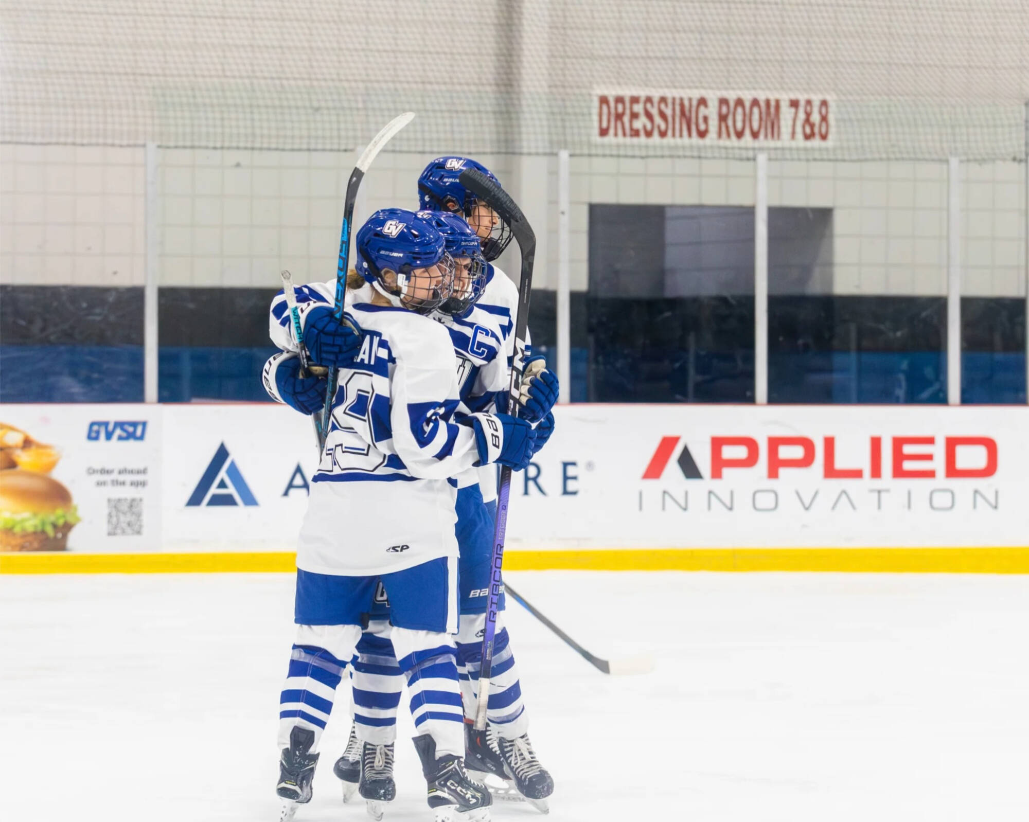 Three women's hockey players embrace in celebration
